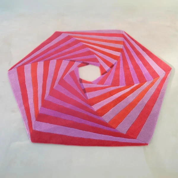 Il dipinto “Swirl” di Annika Johansson trasformato in un tappeto artigianale nei colori rosa e rosso. Tappeto dalla forma esagonale unica con un ritaglio al centro.