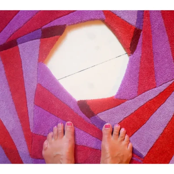 Primo piano del tappeto “Swirl” di Annika Johansson nei colori viola e fucsia, con un esclusivo taglio al centro.