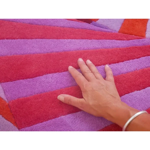 Primo piano del tappeto “Swirl” di Annika Johansson nei colori viola e fucsia, con un esclusivo taglio al centro.