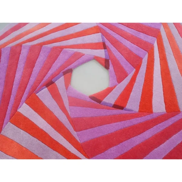 Primo piano del tappeto “Swirl” di Annika Johansson nei colori viola e fucsia, con un esclusivo taglio al centro.