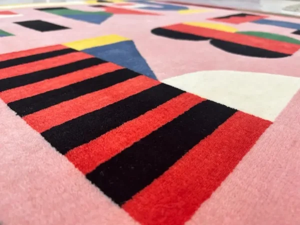 Gros plan sur le tapis artistique personnalisé « Alfabeti » de Camilla Falsini et le tapis rose Rug Your Life avec des lettres colorées