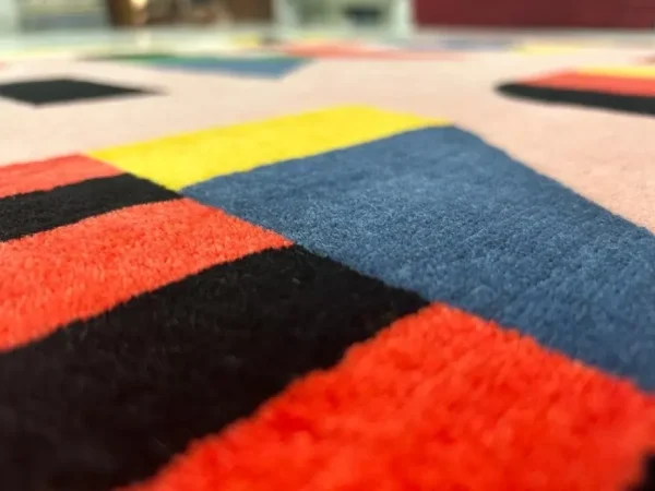 Gros plan sur le tapis artistique personnalisé « Alfabeti » de Camilla Falsini et le tapis rose Rug Your Life avec des lettres colorées