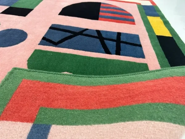 Gros plan sur le tapis artistique personnalisé « Alfabeti » de Camilla Falsini et le tapis rose Rug Your Life avec des lettres colorées