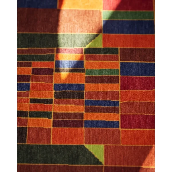 Primo piano del tappeto personalizzato annodato a mano basato sull'opera d'arte "Castello e sole" ("Schloss und Sonne") di Paul Klee, in splendide tonalità calde e terrose.
