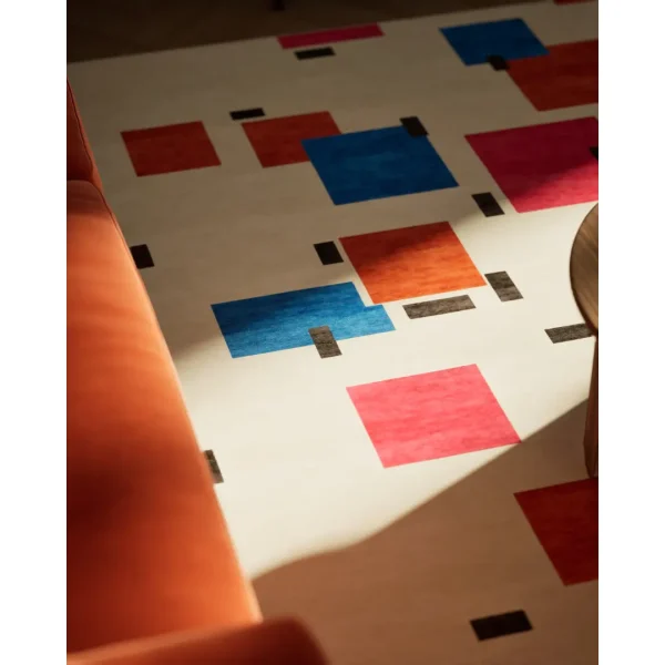 Handgeknüpfter Sonderteppich nach Piet Mondrian "Komposition in Farbe A". Die Basis des Teppichs ist cremefarben und die abstrakten geometrischen Elemente sind in blau, orange, rosa und schwarz gehalten