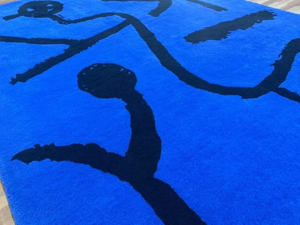 Primer plano de la alfombra hecha a mano a medida por Rug Your Life, inspirada en el cuadro «Dieser Stern lehrt beugen» («Esta estrella enseña a inclinarse») de Paul Klee. Los c La alfombra está fotografiada en un salón.