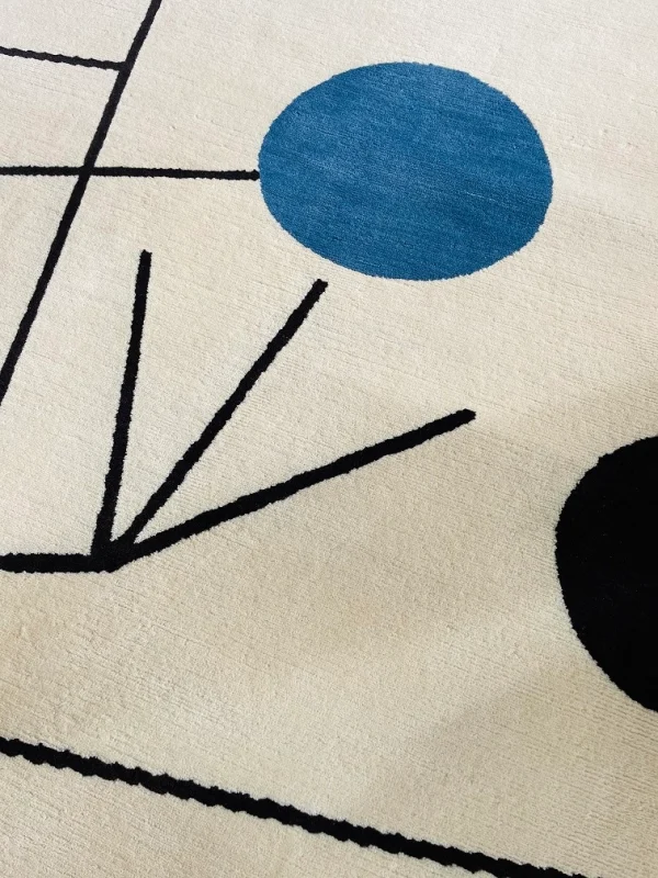 Gros plan du tapis artisanal sur mesure inspiré du tableau « Équilibre » de Sophie Taeuber-Arp. Les couleurs principales du tapis sont le blanc, le jaune, le bleu et le noir. Tapis en édition limitée numérotée, par Rug Your Life.