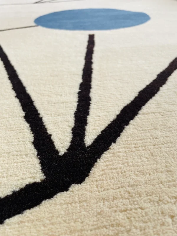 Gros plan du tapis artisanal sur mesure inspiré du tableau « Équilibre » de Sophie Taeuber-Arp. Les couleurs principales du tapis sont le blanc, le jaune, le bleu et le noir. Tapis en édition limitée numérotée, par Rug Your Life.