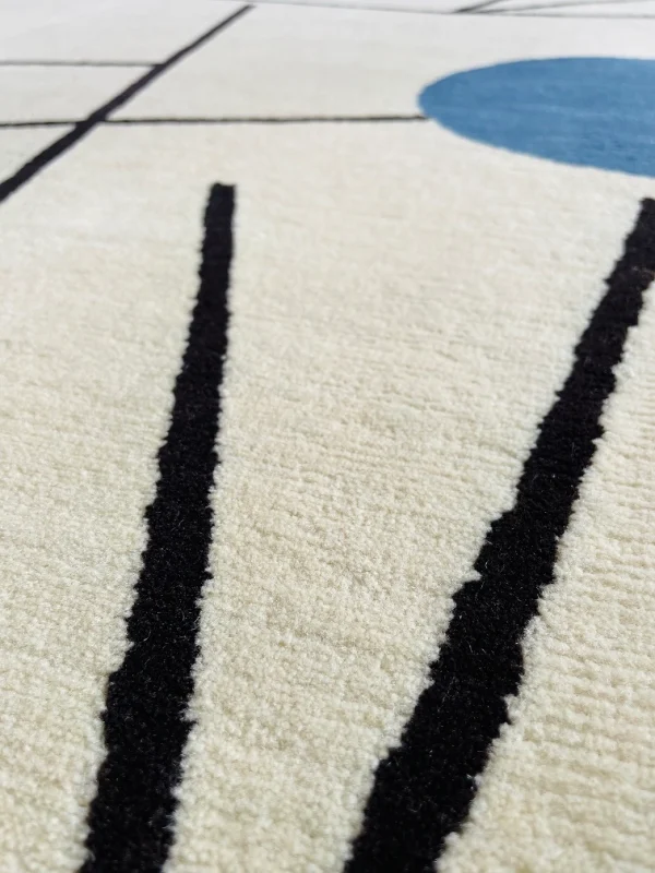 Gros plan du tapis artisanal sur mesure inspiré du tableau « Équilibre » de Sophie Taeuber-Arp. Les couleurs principales du tapis sont le blanc, le jaune, le bleu et le noir. Tapis en édition limitée numérotée, par Rug Your Life.
