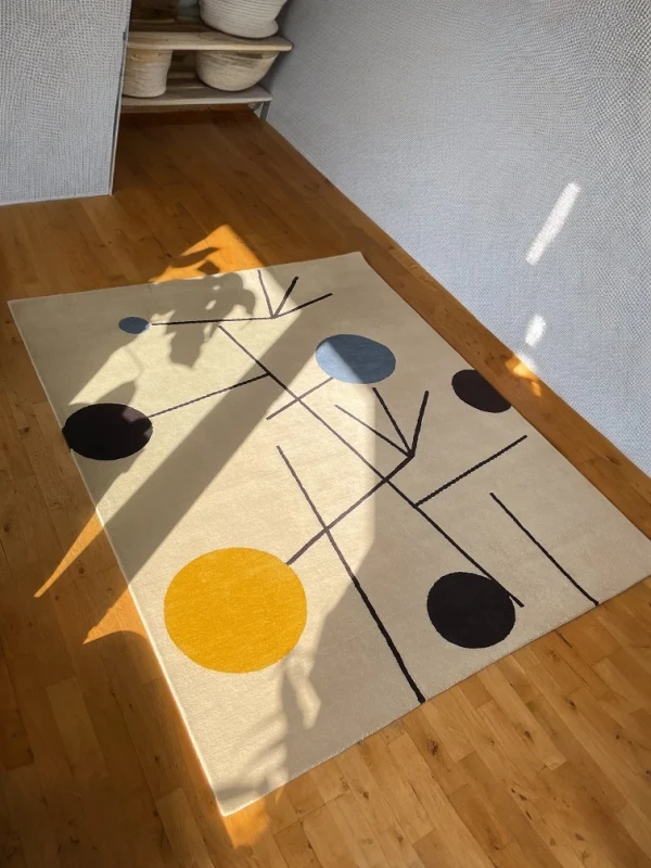 Tapis artisanal sur mesure inspiré du tableau « Équilibre » de Sophie Taeuber-Arp. Les couleurs principales du tapis sont le blanc, le jaune, le bleu et le noir. Tapis en édition limitée numérotée, par Rug Your Life.