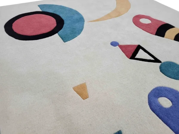 Gros plan sur tapis fait main par Rug Your Life, inspiré du tableau « Composition » (1944) de Wassily Kandinsky. Les couleurs du tapis sont le blanc crème, le bleu, le rouge et le vert.