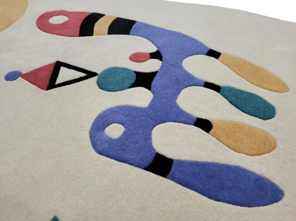 Gros plan sur tapis fait main par Rug Your Life, inspiré du tableau « Composition » (1944) de Wassily Kandinsky. Les couleurs du tapis sont le blanc crème, le bleu, le rouge et le vert.
