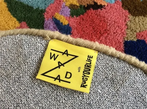 Primer plano de la etiqueta de la alfombra Zawada, colección de alfombras Affordances de Jonathan Zawada y Rug Your Life.